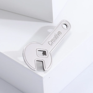 Detail showing creative silver wrench brooch with engraved creative text on a white pedestal