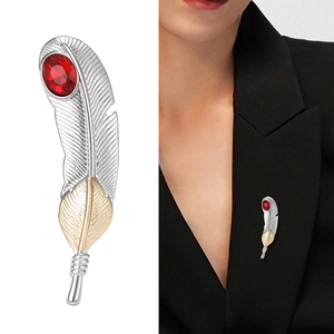 Feather brooch in silver and gold tones with a red gemstone on a suit lapel