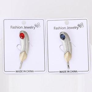 Detail of feather brooches with red and blue stones in silver and gold dual-tone finish