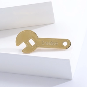 Creative gold wrench brooch pin with embossed text on minimalist geometric display