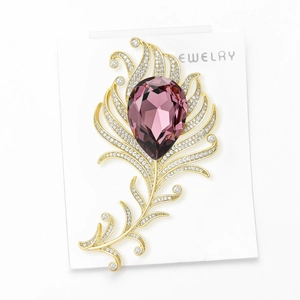 Close-up of golden feather brooch with large purple pear-shaped zircon and pave setting