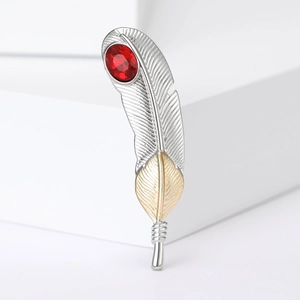 Detailed close-up of a feather brooch with a red gemstone and gold-silver metal finish