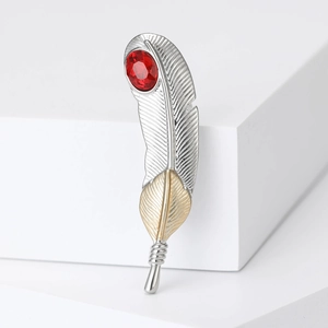 Detailed macro view of feather brooch with red gemstone on white geometric block