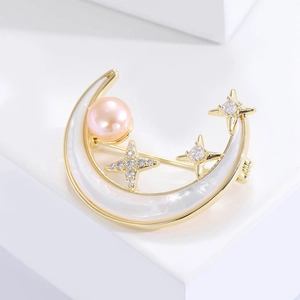 Macro de la broche lune dorée avec perle d'eau douce rose et détails d'étoiles scintillantes
