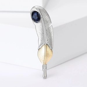 Detail of feather brooch with silver metal, gold accents and blue gemstone inlay