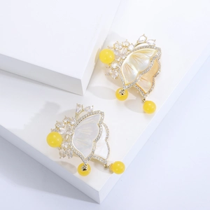 Detailed macro view of golden butterfly pins with mother of pearl and zircon stones