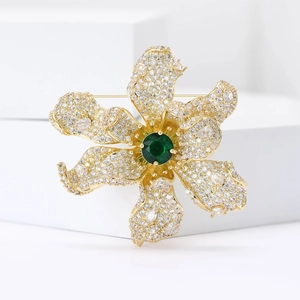 Exquisite flower brooch with green zircon center and sparkling white stones on gold base