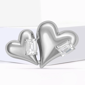 Broche cœur élégante en métal argenté avec zircons taille émeraude sur présentoir blanc