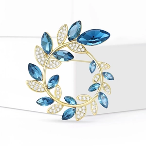 Broche couronne de feuilles dorée avec cristaux bleu foncé et zircons blancs scintillants