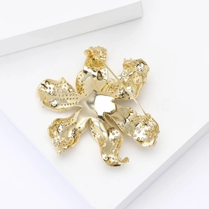 Back view of a gold flower brooch showing the secure pin fastener and hollow metalwork