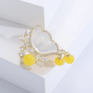 Detail of luxury butterfly brooch with shell wings, gold plating and amber-like beads