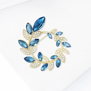 Détail d'une broche couronne dorée avec cristaux bleu marine et zircons brillants
