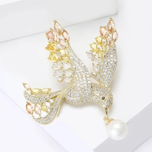 Elegant gold bird brooch with sparkling yellow gemstones and a white pearl drop