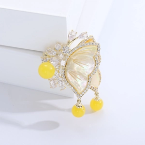 Macro detail of luxury butterfly brooch with mother of pearl inlay and yellow beads