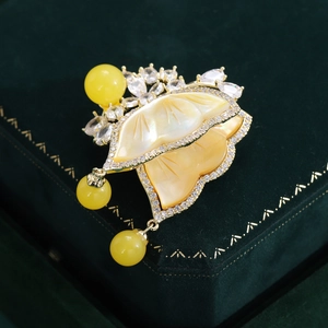 Detail view of gold butterfly brooch with mother of pearl and yellow resin bead accents