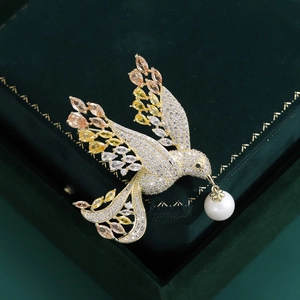 Detailed close-up of a gold bird brooch with multi-colored stones and a white pearl accent