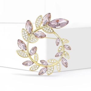Détail d'une broche couronne d'olivier dorée avec cristaux roses et pavé de diamants