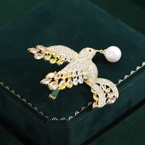 Macro detail of a golden bird brooch with colorful zircons and a white pearl on velvet