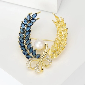 Detailed macro view of wheat wreath brooch with blue gems, pearls, and a golden bow