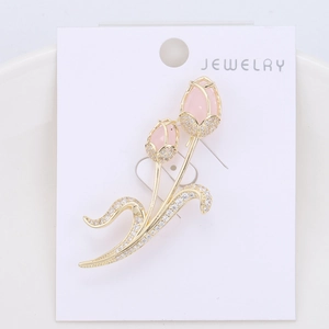 Detail shot of golden tulip brooch with pink stones and zircon leaves on jewelry card