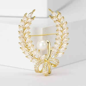 Macro detail of vintage gold wheat wreath brooch with crystal leaves and a center pearl