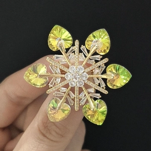Macro detail of snowflake brooch featuring heart-shaped crystal petals and gold plating