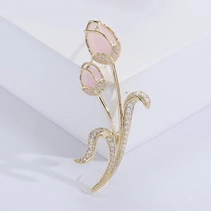 Elegant gold tulip brooch with pink gemstones and white micro zircons on a white display