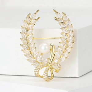 Macro shot of laurel wreath brooch with marquise zircons, gold ribbon and white pearl