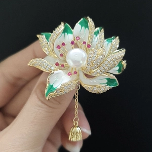 Exquisite lotus brooch detail with green enamel petals, white pearl and red gemstones