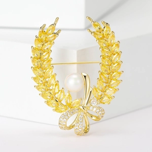 Macro detail of wheat ear brooch with yellow zircons, pearl, and bowknot accent