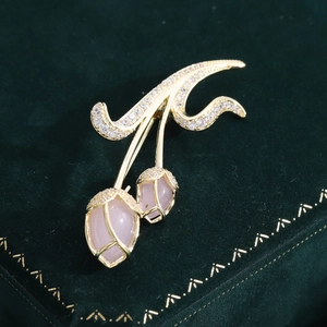 Elegant gold tulip brooch with pink gems and zircons on green velvet background
