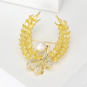 Detailed close-up of golden wheat brooch with yellow stones and a white center pearl