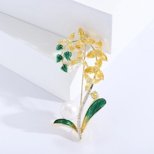 Détail de broche orchidée avec cristaux jaunes, émail vert et une perle blanche