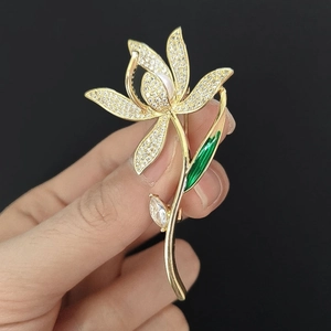 Détail de la broche orchidée dorée avec pétales en zircon et perle blanche élégante