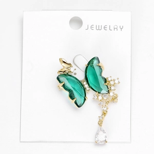 Detailed macro view of crystal butterfly brooch with emerald green stones and gold plating