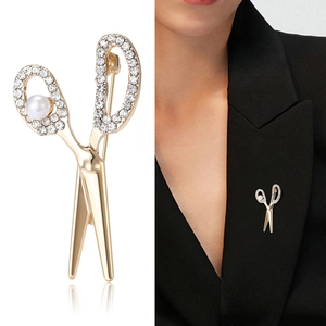 Creative gold scissor brooch with sparkling rhinestones and pearl on black blazer lapel