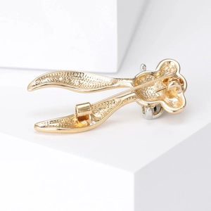 Golden long-eared rabbit brooch with detailed textured finish on minimalist pedestal