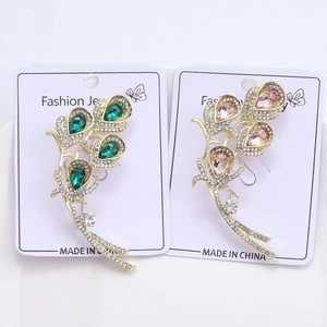Detail of elegant feather-shaped brooches with colorful rhinestones on display card