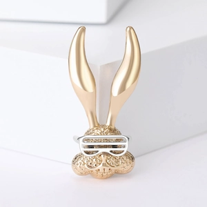 Detailed view of golden rabbit brooch with textured surface and silver sunglasses