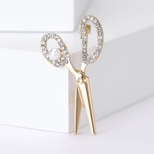 Detailed view of scissors brooch with gold plating, sparkling rhinestones, and pearl accent