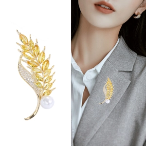 Elegant gold wheat ear brooch with yellow zircon and white pearl on a gray suit