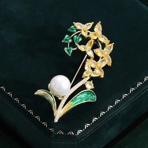 Détail de la broche fleur avec feuilles en émail vert, cristaux jaunes et perle