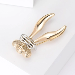 Detail of creative long-eared rabbit brooch with bicolored metal texture on white steps