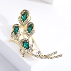 Elegant gold feather brooch with green pear-shaped gemstones and sparkling rhinestones