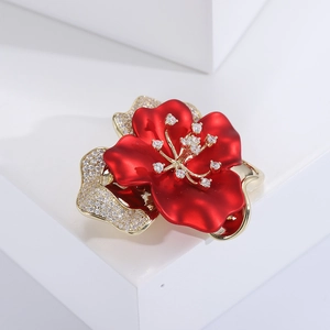 Dettaglio ravvicinato di una spilla a fiore con zirconi e petali in smalto rosso