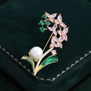 Détail de la broche fleur avec cristaux roses, feuilles en émail vert et perle blanche