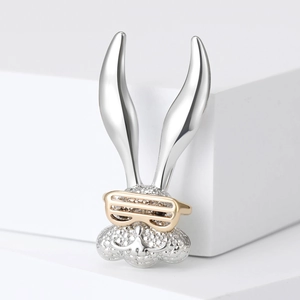 Macro detail of silver long-eared rabbit brooch with crystal inlay and golden sunglasses