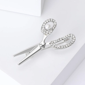 Macro shot of silver scissor brooch with white rhinestones and a round white pearl inlay