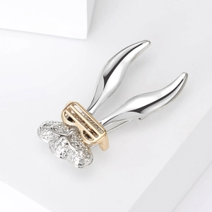 Detail of silver long rabbit ears brooch with hollow carved ball and golden bow decor