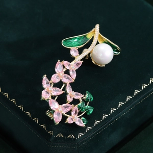 Détail d'une broche florale avec feuilles en émail vert, zircons roses et perles